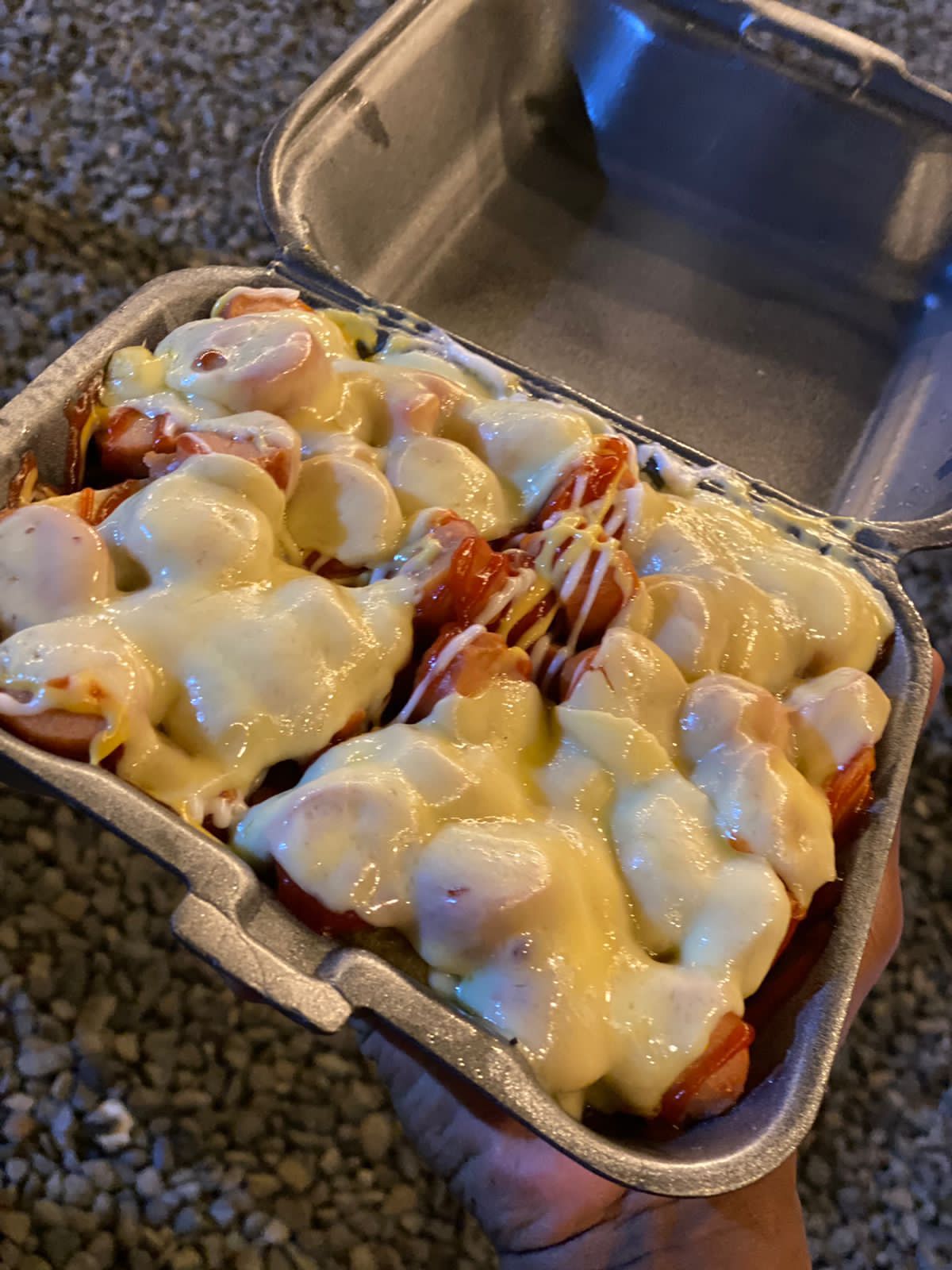 Hot dog bañado en queso en caja para llevar